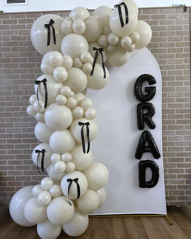 Cream and bone garland tied with satin bows on exposed brick, built by Sherri's Heavenly Balloons in central Indiana.