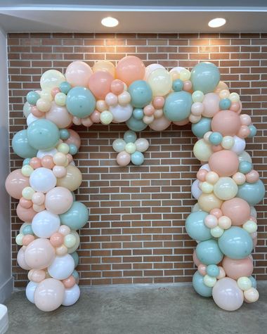 Mint, peach and pearl arch across a brick doorway, built by Sherri's Heavenly Balloons in central Indiana.